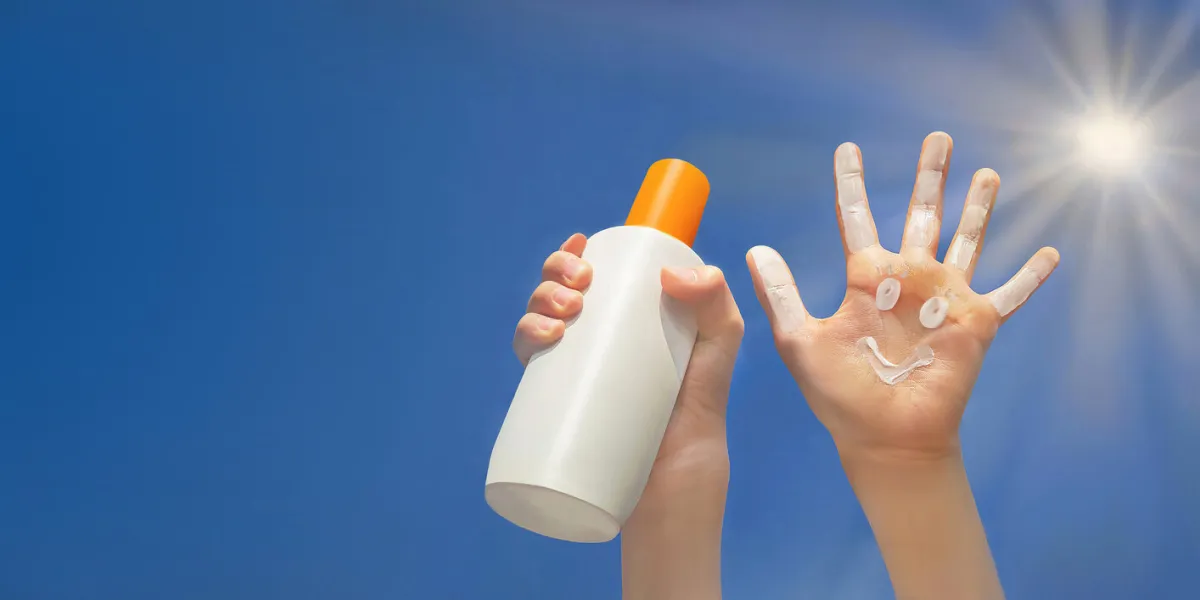 positive symbol drawing by sunscreen on open hand another hand holding a bottle of sun cream blue sky, beams of sun background protection of sun copy space positive symbol drawing by sunscreen on open hand another hand holding a bottle of sun cream blue sky, beams of sun background protection of sun copy space
