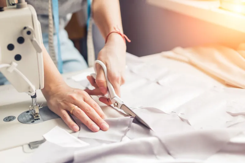 pattern, scissors, tape measure, and a sewing machine workplace of seamstress dressmaker cuts dress detail on the sketch lines pattern, scissors, tape measure, and a sewing machine workplace of seamstress dressmaker cuts dress detail on the sketch lines