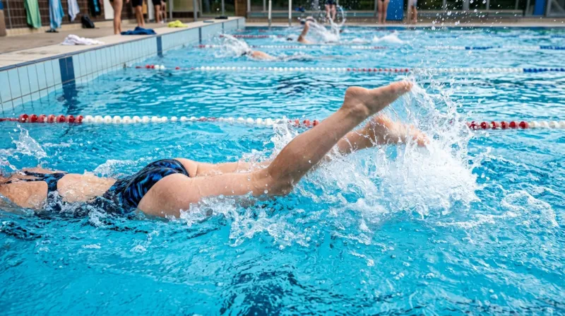 Une photo de jambes effectuant des battements rapides dans l'eau d'une piscine créant des remous vig
