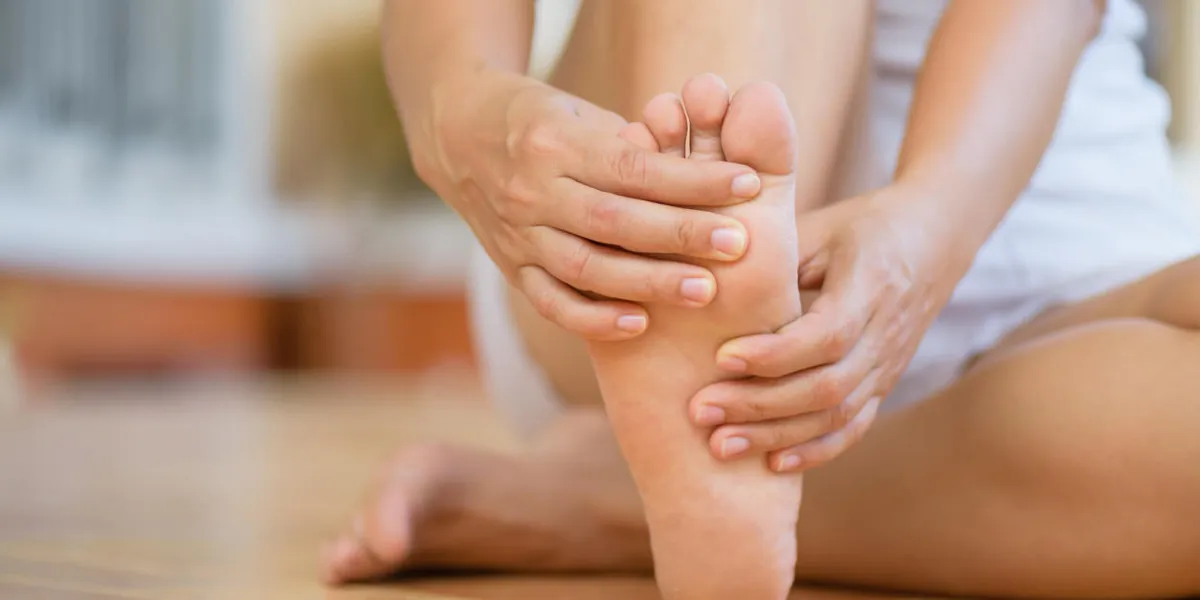 closeup young woman feeling pain in her foot at home healthcare and medical concept closeup young woman feeling pain in her foot at home healthcare and medical concept