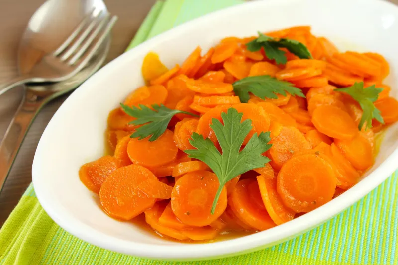 carottes tranchées cuites avec des feuilles de persil frais servi sur une plaque ovale blanche carottes tranchées cuites avec des feuilles de persil frais servi sur une plaque ovale blanche