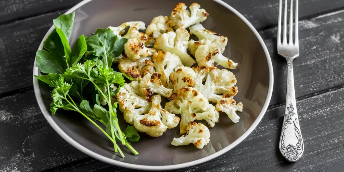 chou-fleur rôti et salade verte fraîche sur une plaque brune sur un fond en bois foncé chou-fleur rôti et salade verte fraîche sur une plaque brune sur un fond en bois foncé