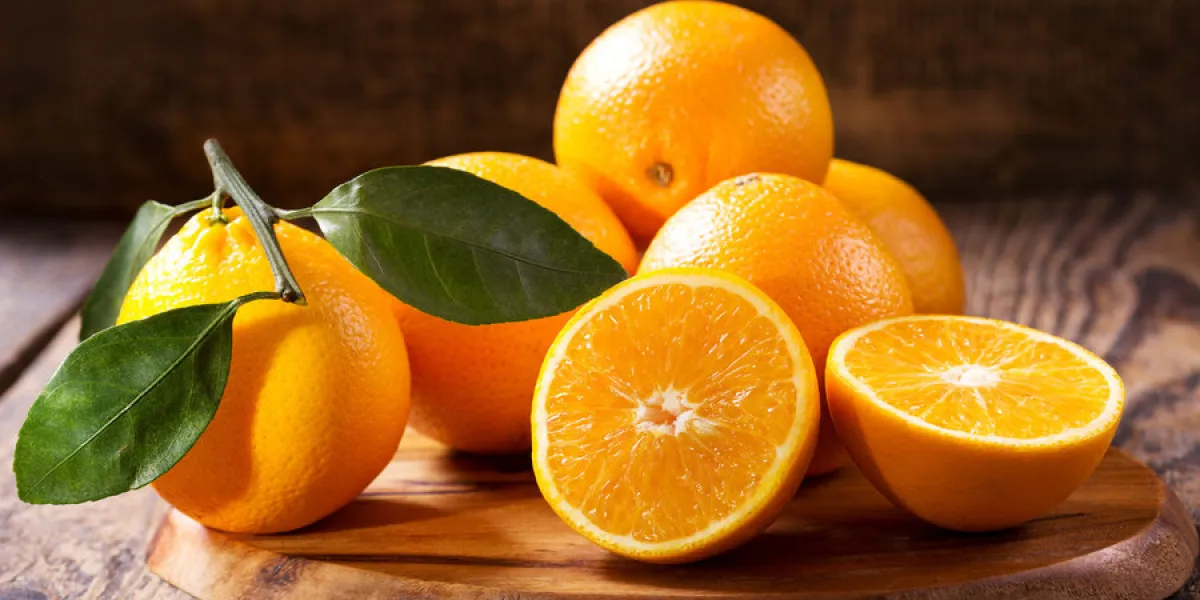 fresh orange fruits with leaves on wooden table