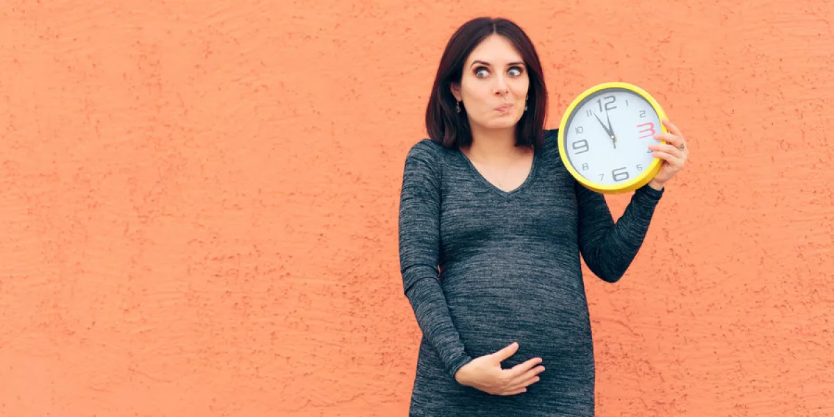 cheerful girl holding a clock awaiting her baby cheerful girl holding a clock awaiting her baby