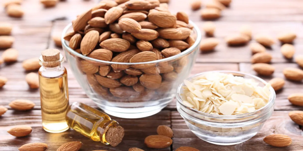 almond and oil in bottles on brown wooden table almond and oil in bottles on brown wooden table