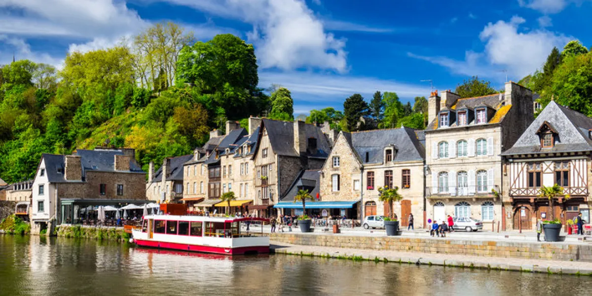 beautiful view of scenic narrow alley with historic traditional houses and cobbled street in an old town of dinan with blue sky and clouds brittany (bretagne), france