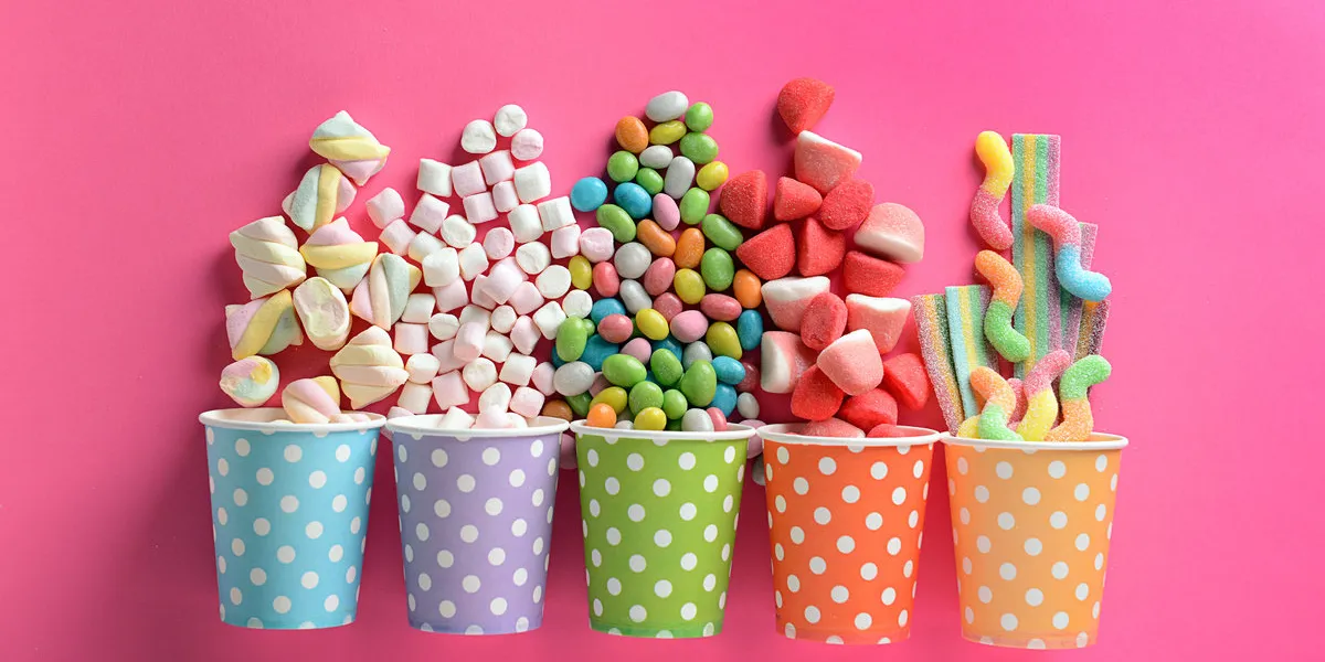 paper cups with tasty candies on color background paper cups with tasty candies on color background