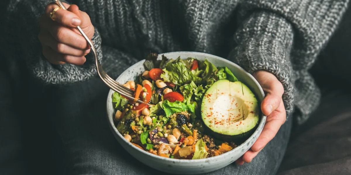 healthy vegetarian dinner woman in jeans and warm sweater holding bowl with fresh salad, avocado, grains, beans, roasted vegetables, close-up superfood, clean eating, vegan, dieting food concept
