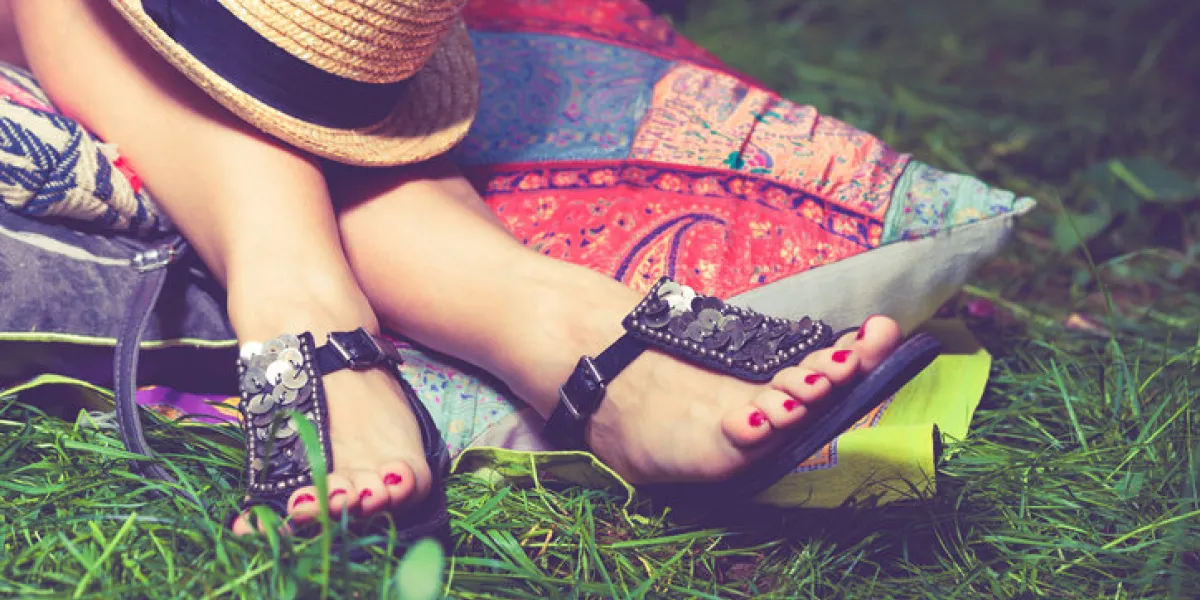 woman feet on grass in flat summer sandals lean on pillows hat lay on legs woman feet on grass in flat summer sandals lean on pillows hat lay on legs