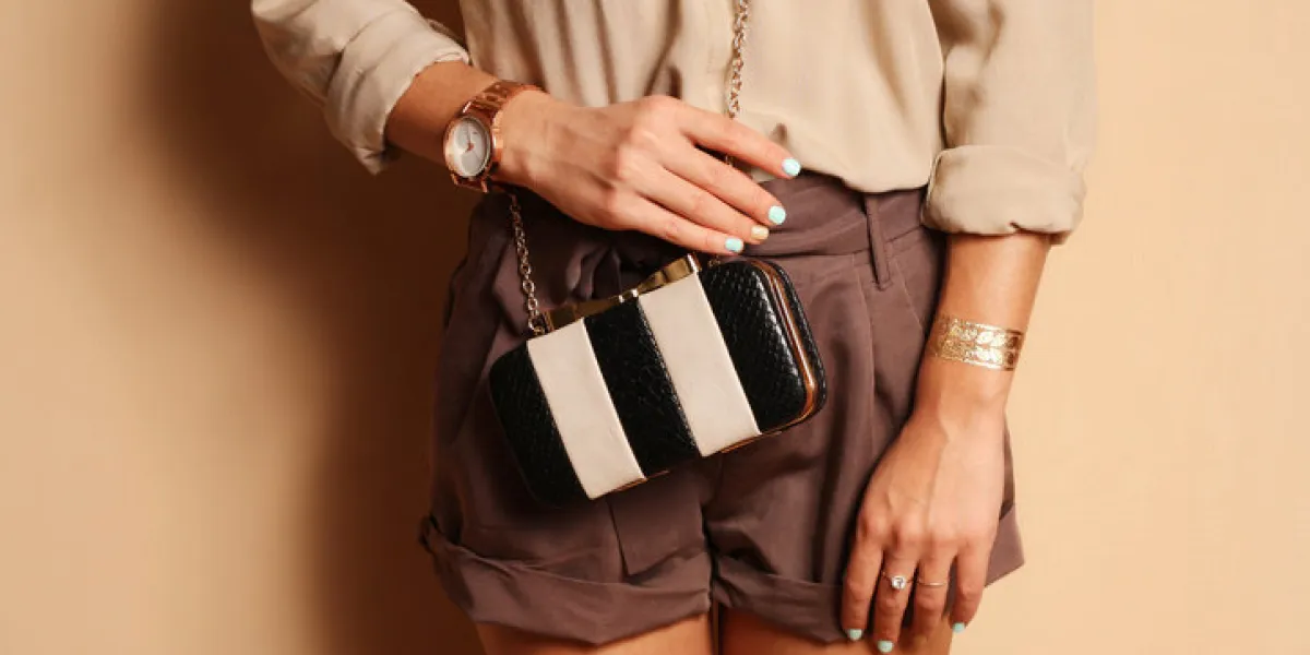 fashionable woman with stylish black and white clutch , accessories, watch elegant outfit silk blouse and brown shorts fashionable woman with stylish black and white clutch , accessories, watch elegant outfit silk blouse and brown shorts