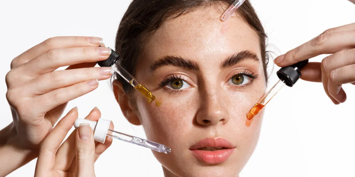 beauty face of woman with freckles, natural clean and fresh glowing skin, apply anti-aging collagen serum hands holding serum with active botanical ingredients vitamin c in dropper, white background