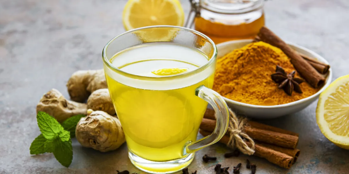 energy tonic drink with turmeric, ginger, lemon and honey on a grey concrete background