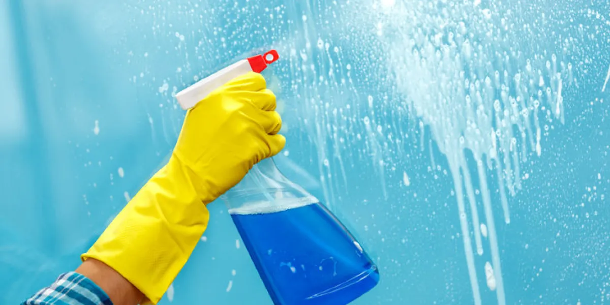 studio shot through glass of housekeeper woman hand with glove holding bottle of spray focus on hand studio shot through glass of housekeeper woman hand with glove holding bottle of spray focus on hand