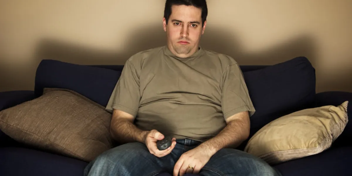 bored, lazy, overweight man sits on the sofa