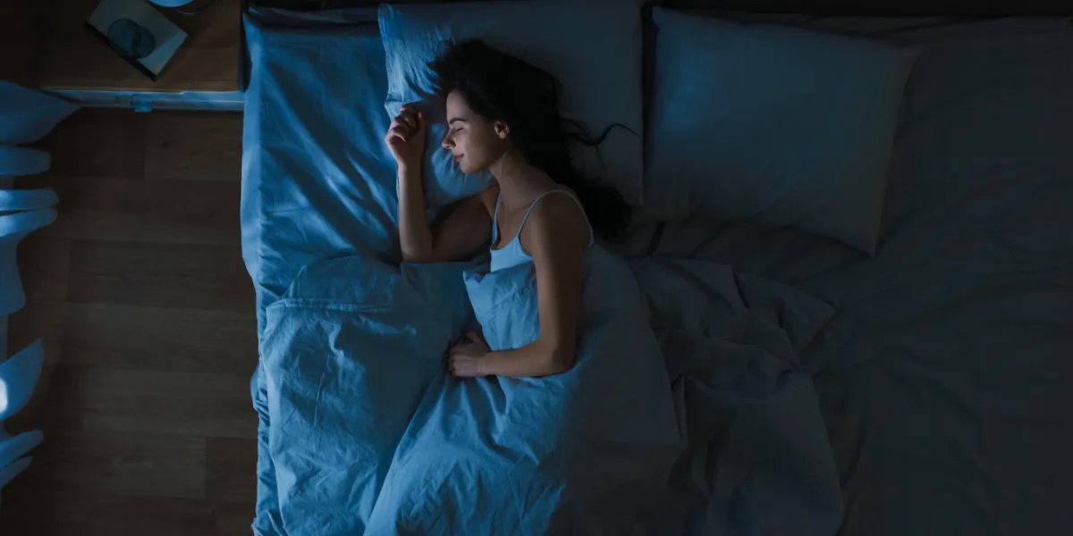 top view of beautiful young woman sleeping cozily on a bed in his bedroom at night blue nightly colors with cold weak lamppost light shining through the window top view of beautiful young woman sleeping cozily on a bed in his bedroom at night blue nightly colors with cold weak lamppost light shining through the window