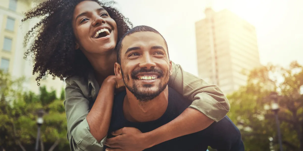 cheerful young man giving piggyback ride to his girlfriend outdoors in the city cheerful young man giving piggyback ride to his girlfriend outdoors in the city