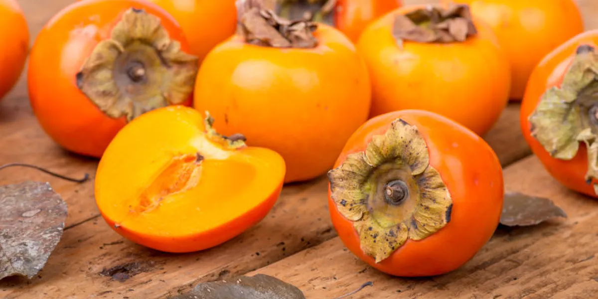 fresh ripe persimmon on a wooden table - selective focus
