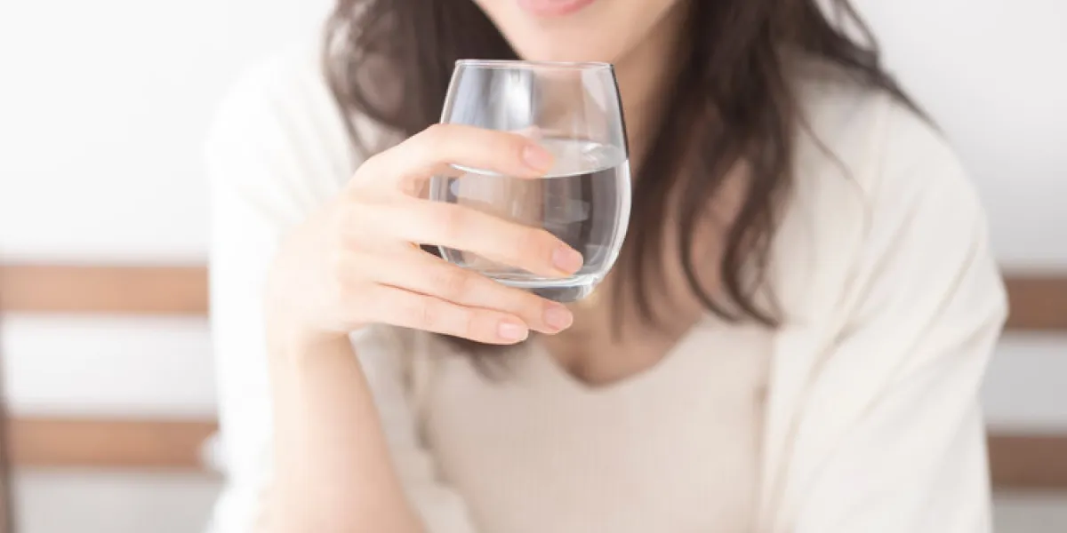 ベッドで水を飲む女性