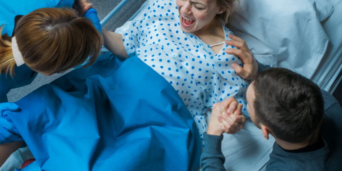 in the hospital woman in labor pushes to give birth, obstetricians assisting, husband holds her hand for support modern maternity ward with professional midwives in the hospital woman in labor pushes to give birth, obstetricians assisting, husband holds her hand for support modern maternity ward with professional midwives