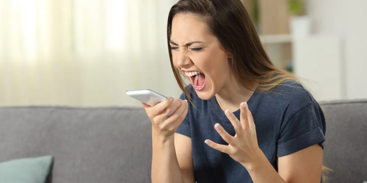 furious woman shouting to smart phone sitting on a couch in the living room at home furious woman shouting to smart phone sitting on a couch in the living room at home