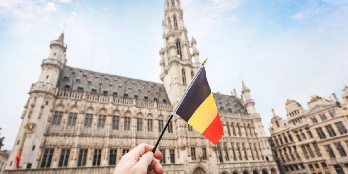 woman tourist holds in her hand a flag of belgium against the background of the grand-place square in brussels, belgium traveling in belgium, the main attraction of brussels, the grand market square woman tourist holds in her hand a flag of belgium against the background of the grand-place square in brussels, belgium traveling in belgium, the main attraction of brussels, the grand market square