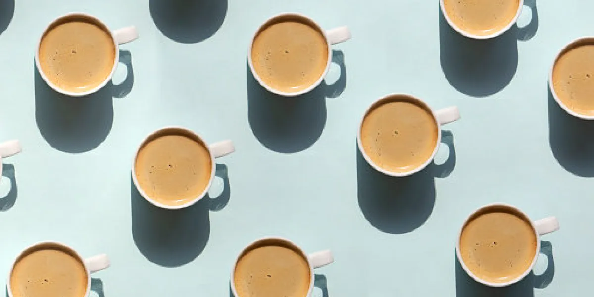 pattern made of cup of cappuccino on blue background pattern made of cup of cappuccino on blue background
