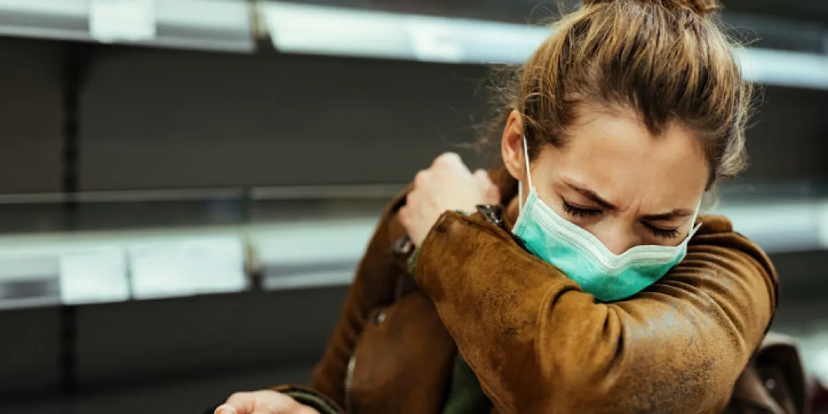 sick woman buying in supermarket and coughing into elbow during covid-19 pandemic sick woman buying in supermarket and coughing into elbow during covid-19 pandemic