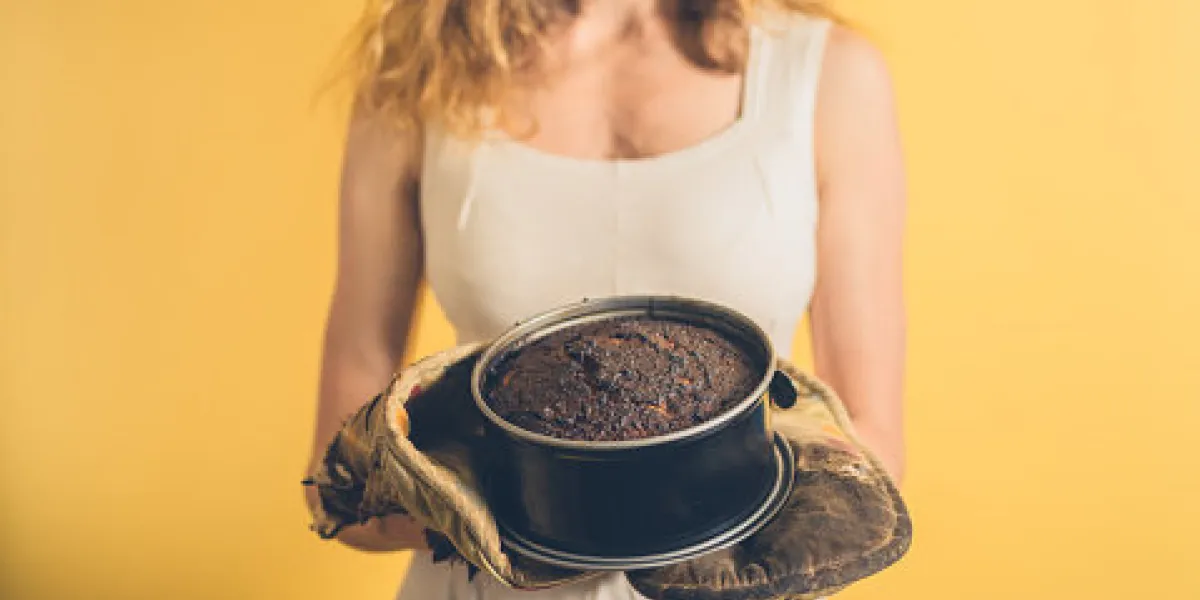 a young woman is holding a burnt cake with burnt oven gloves a young woman is holding a burnt cake with burnt oven gloves