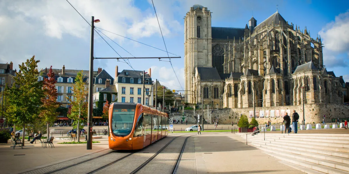 le mans, france - october 08, 2017 roman cathedral of saint julien with an orange tram at a le mans sarthe, pays de la loire, france le mans, france - october 08, 2017 roman cathedral of saint julien with an orange tram at a le mans sarthe, pays de la loire, france