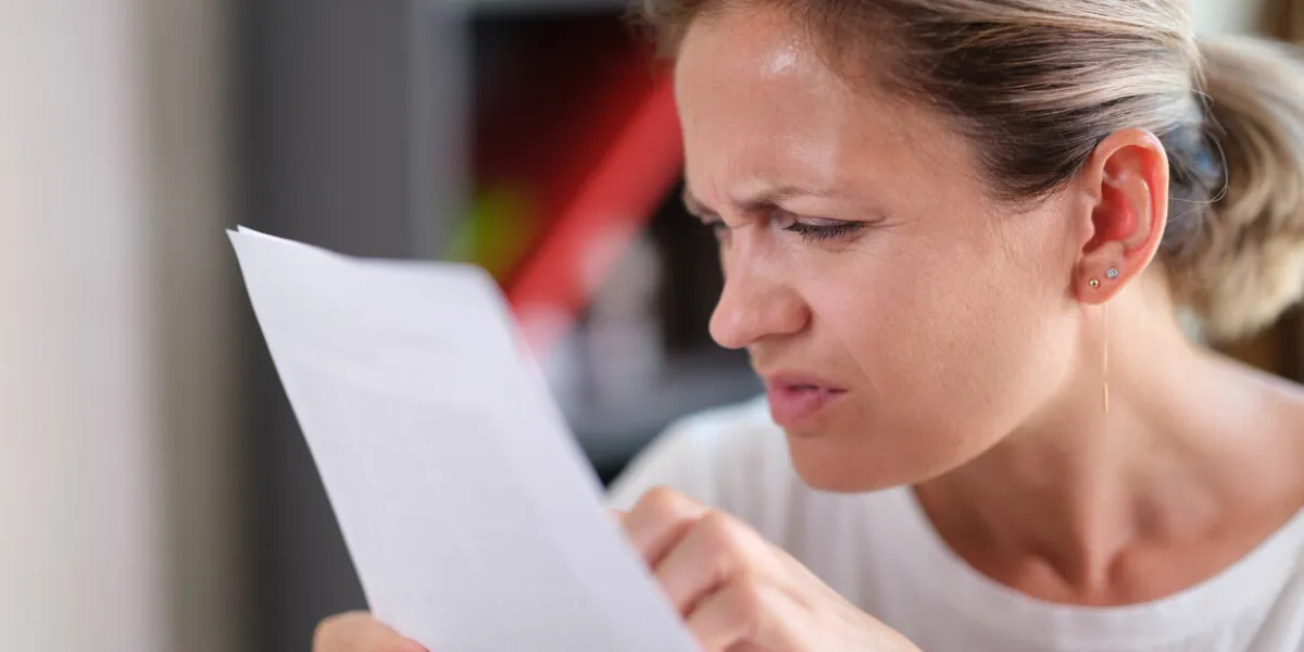 portrait of focused female trying read text, squinting to see more clearly female having difficulties seeing text because of vision problems portrait of focused female trying read text, squinting to see more clearly female having difficulties seeing text because of vision problems