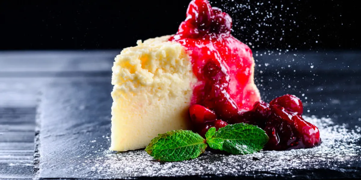 cheesecake brownies with cherry sauce, cherry cheesecake on a black background with reflection and flying icing sugar cheesecake brownies with cherry sauce, cherry cheesecake on a black background with reflection and flying icing sugar