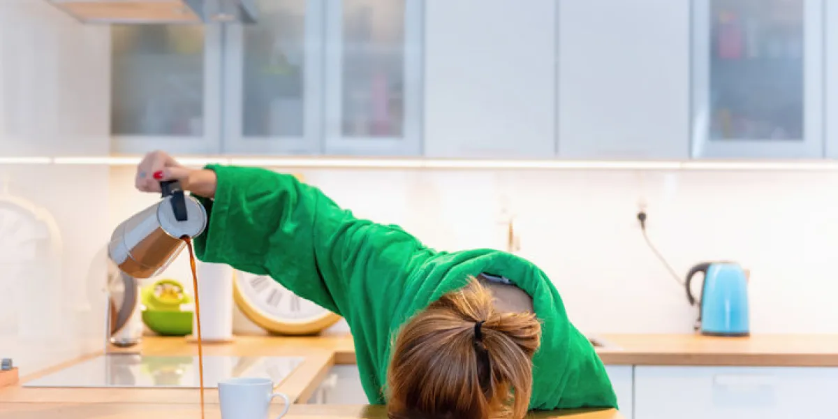 tired woman sleeping on the table in the kitchen at breakfast trying to drink morning coffee tired woman sleeping on the table in the kitchen at breakfast trying to drink morning coffee