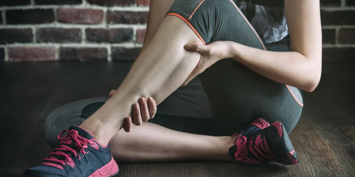 have a leg cramp in fitness exercise training, healthy lifestyle concept, indoors gym wooden floor brick wall background