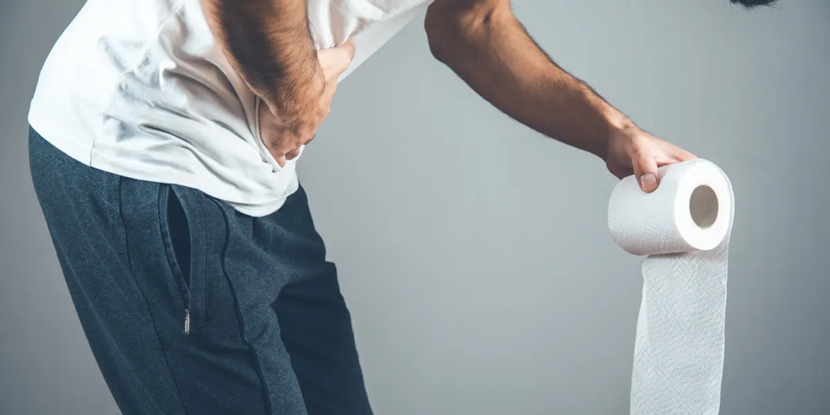 man holding a roll of toilet paper on gray background man holding a roll of toilet paper on gray background