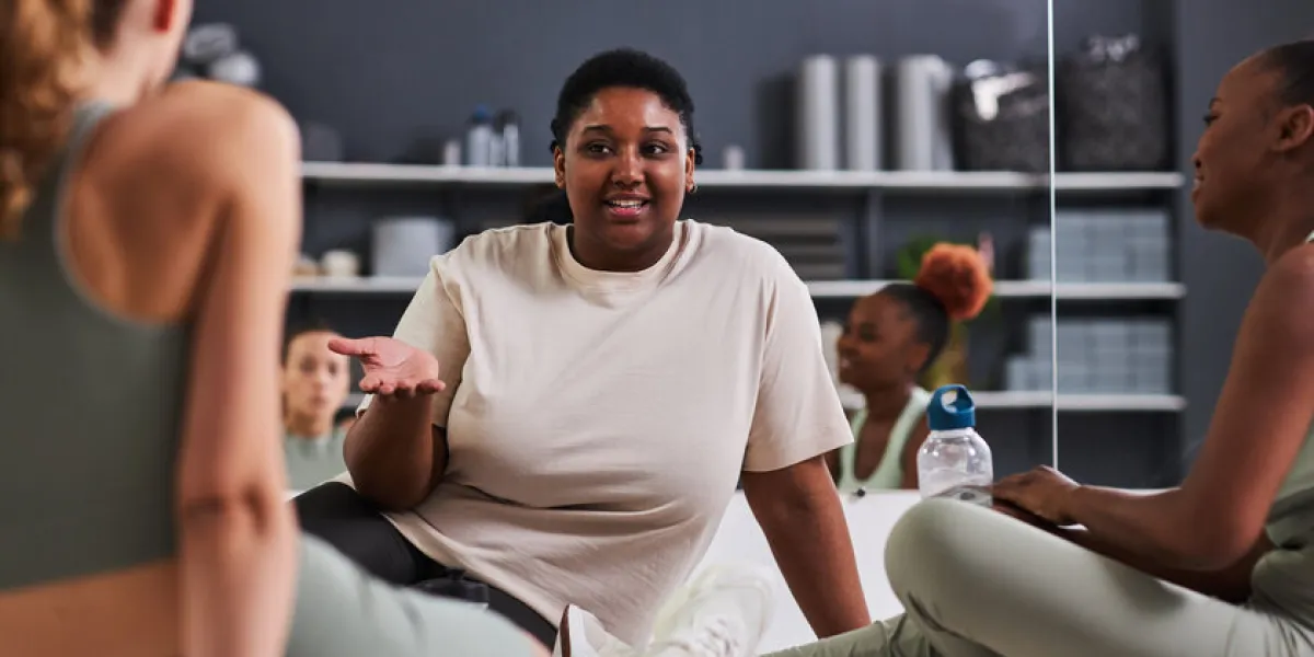 group of young women sitting on the floor and talking to each other during training in gym group of young women sitting on the floor and talking to each other during training in gym