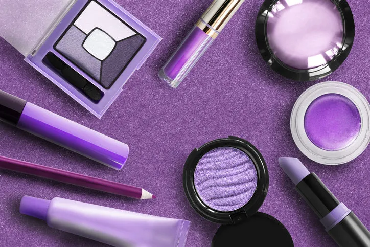 cosmetics collection in shades of purple on paper background