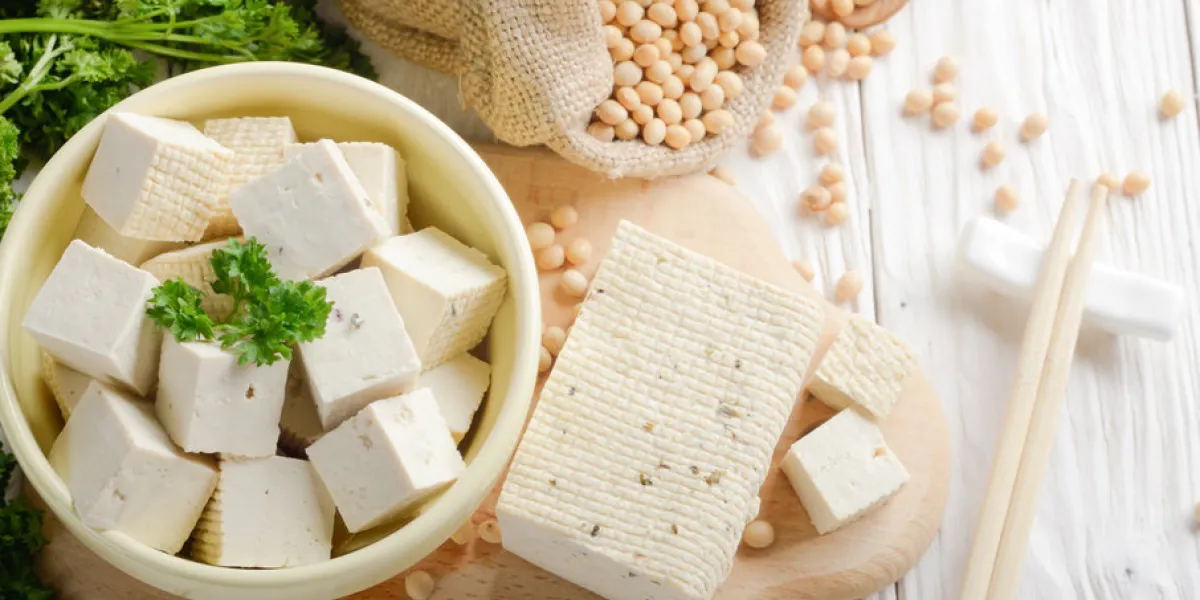 soy bean curd tofu in clay bowl and in hemp sack on white wooden kitchen table non-dairy alternative substitute for cheese place for text