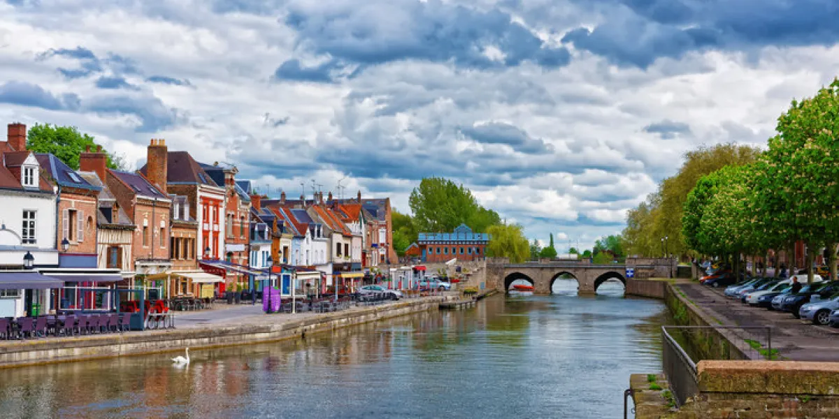 amiens, france - may 9, 2012 quay of belu with traditional houses and somme river in amiens, picardy, france people on the background amiens, france - may 9, 2012 quay of belu with traditional houses and somme river in amiens, picardy, france people on the background