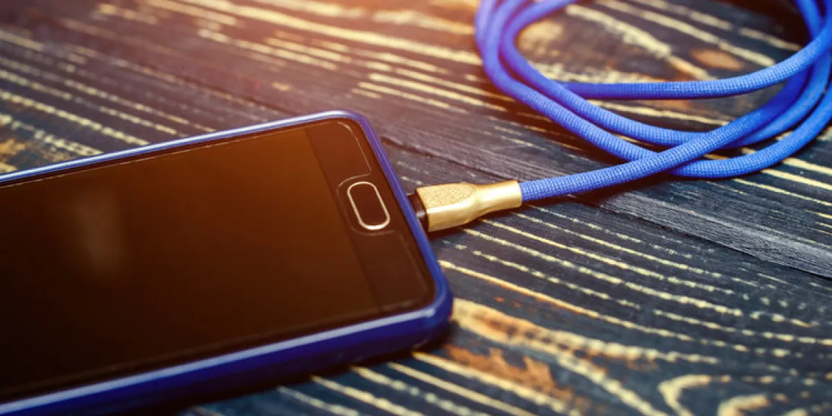 mobile phone and charger on brown wooden background mobile phone and charger on brown wooden background