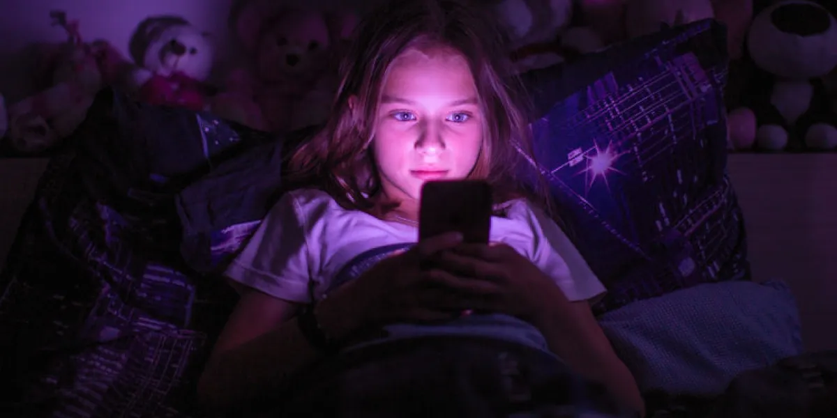 little girl lying under a blanket looking at the smartphone at night little girl lying under a blanket looking at the smartphone at night