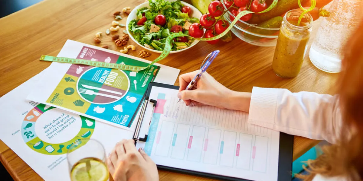 woman dietitian in medical uniform with tape measure working on a diet plan sitting with different healthy food ingredients in the green office on background weight loss and right nutrition concept woman dietitian in medical uniform with tape measure working on a diet plan sitting with different healthy food ingredients in the green office on background weight loss and right nutrition concept