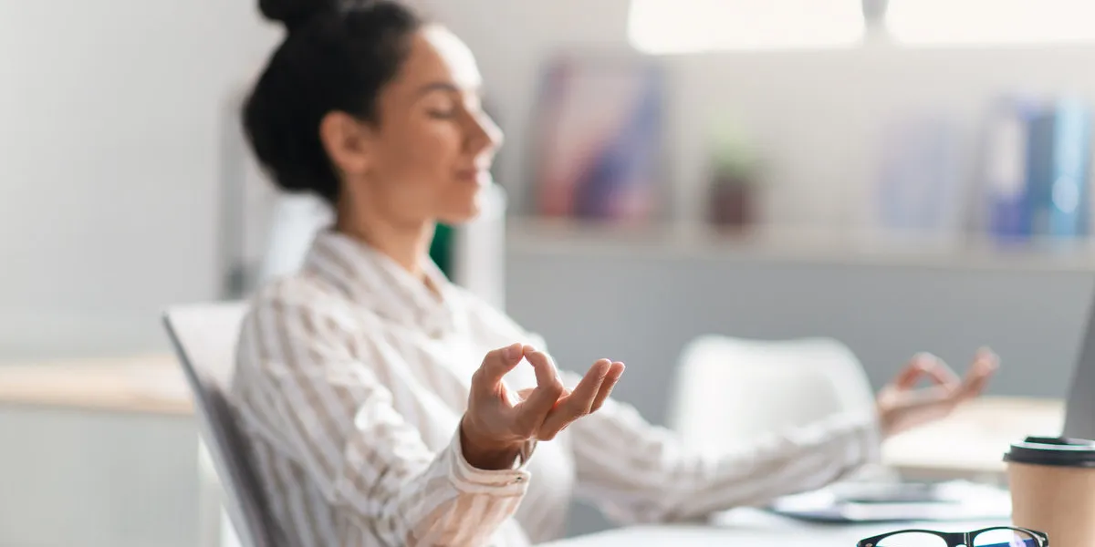 workplace stress management female entrepreneur meditating and relaxing during stressful day, sitting at workplace in office interior focus on hand mental hygiene concept