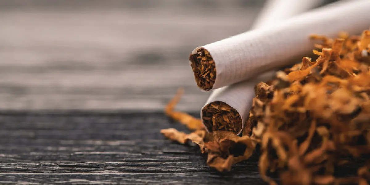 cigarettes and tobacco on a black wooden background cigarettes and tobacco on a black wooden background