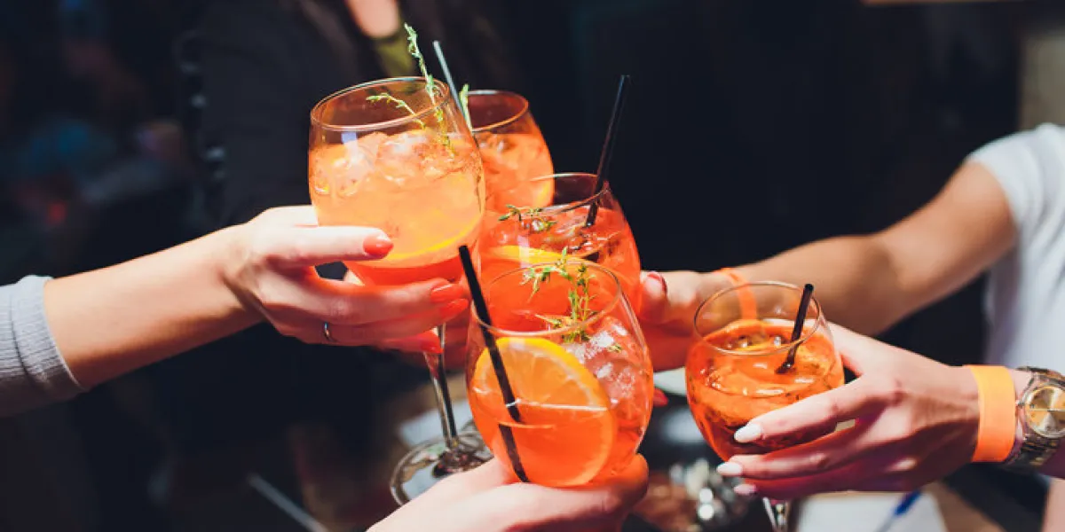 women raising a glasses of spritz at the dinner table