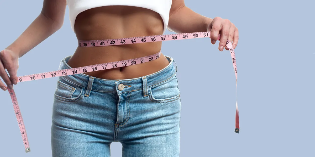 diet concept woman is measuring waist after weight loss on pastel background diet concept woman is measuring waist after weight loss on pastel background