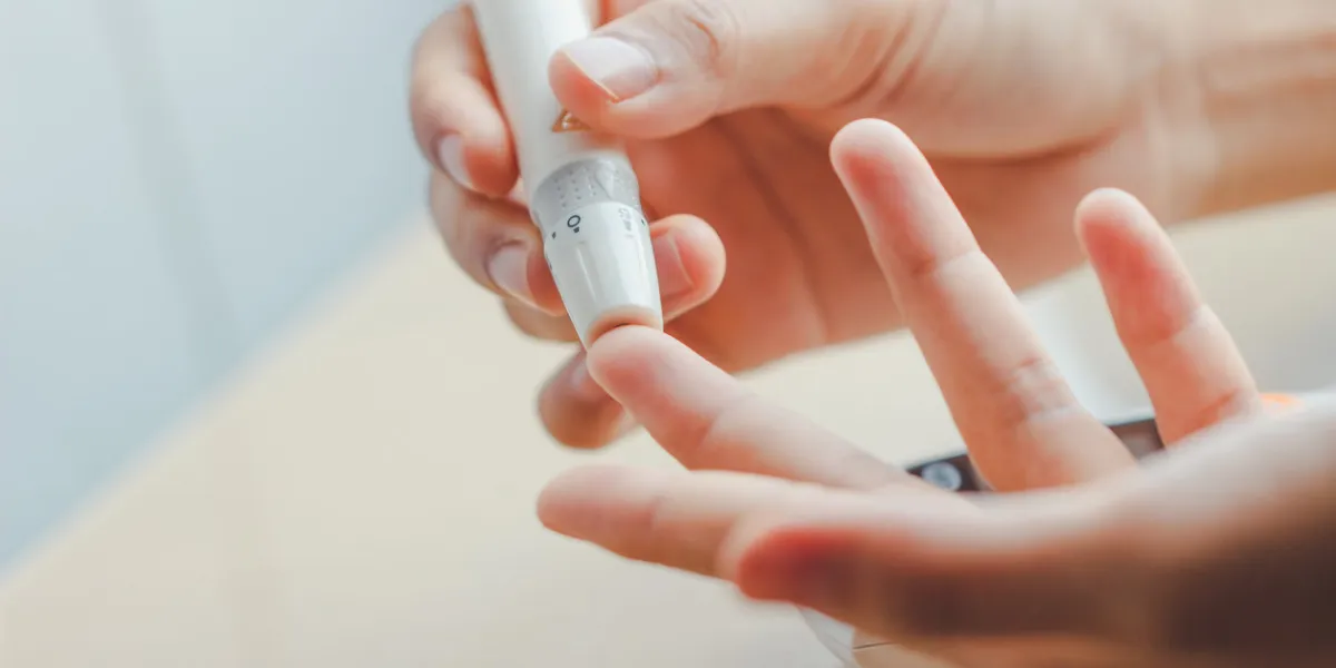 close up of woman hands using lancet on finger to check blood sugar level by glucose meter using as medicine, diabetes, glycemia, health care and people concept