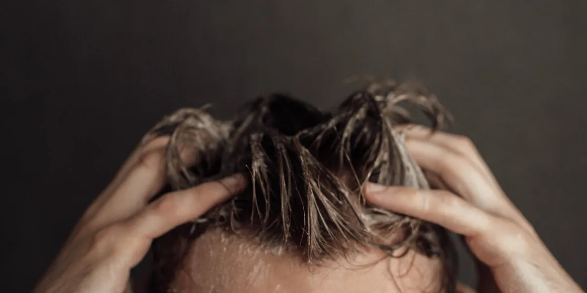 a man washes his hair  hands and wet hair in shampoo foam