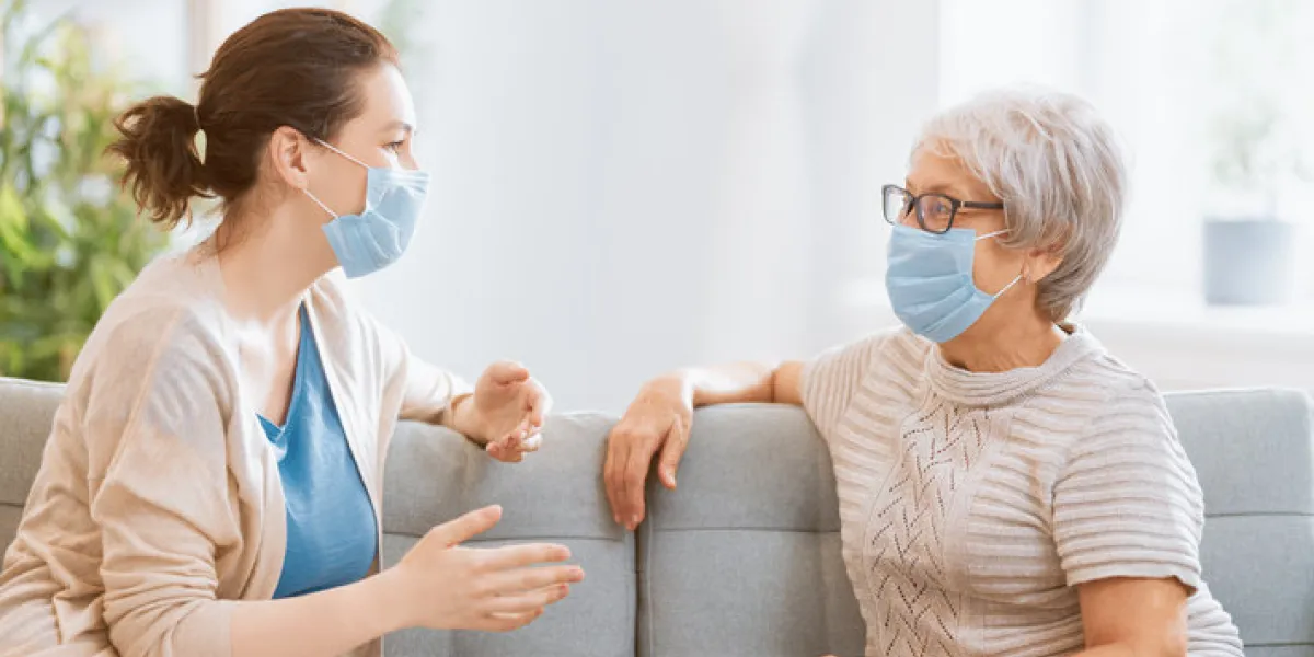 adult daughter and senior parent wearing facemasks during coronavirus and flu outbreak virus and illness protection, home quarantine covid-2019