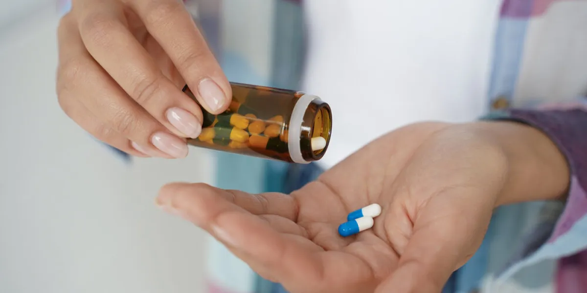female holding pills taking dietary supplements, vitamins or medicines, close up woman's hands pours medical capsules out of jar into palm to take painkiller or sleeping tablets for treatment