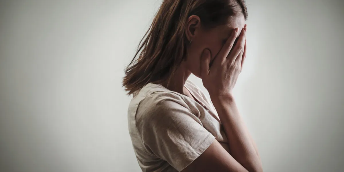 portrait of depressed woman, covering face with her hands, side view